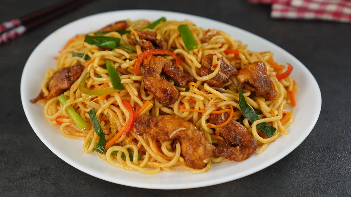 hicken chow mein served in a white bowl with chopsticks