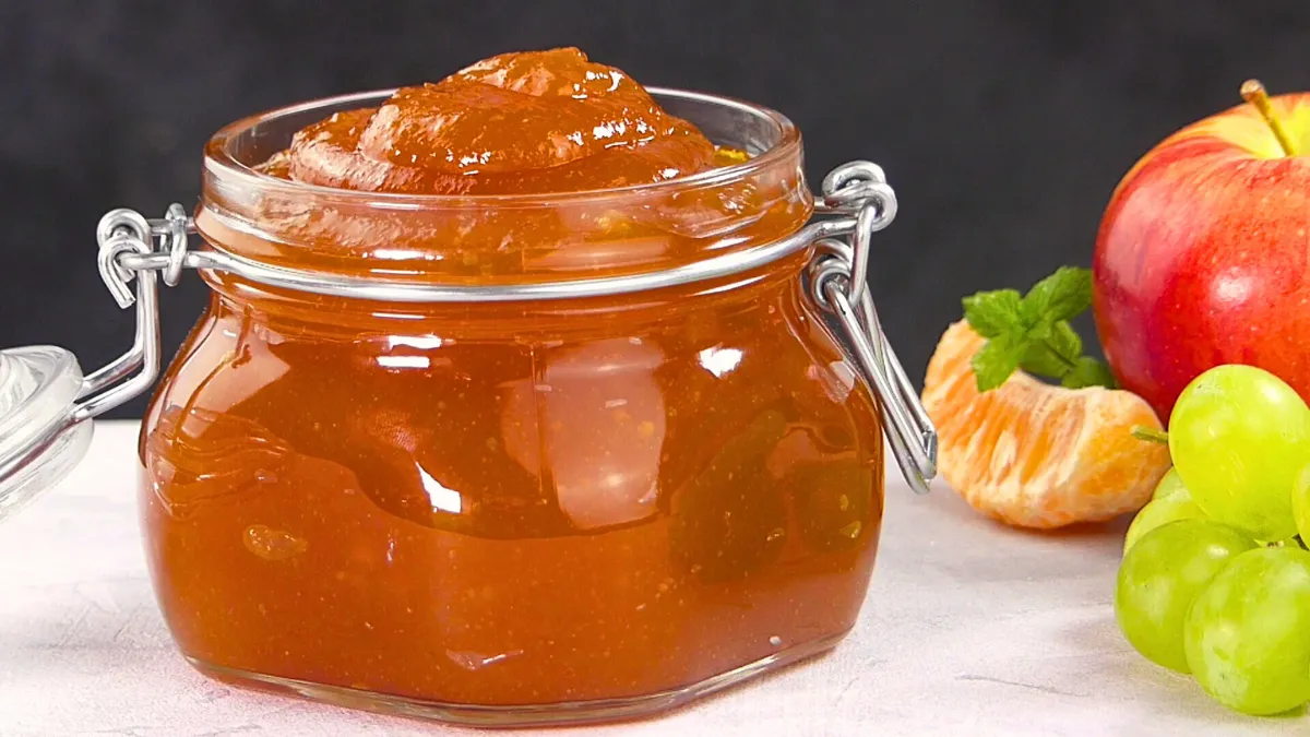 A jar of homemade mixed fruit jam next to sliced bread